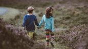 Jongen en meisje lopend hand in hand door de natuur