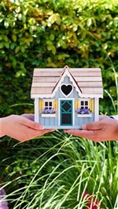 Twee handen die een miniatuurhuisje vasthouden